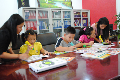 Nhân viên Công ty TNHH Tin học TH Nha Trang hướng dẫn các bé sử dụng bút nói và sách nói điện tử.