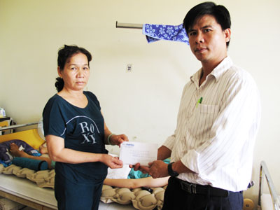 Đại diện Báo Khánh Hòa (bên phải) trao tiền ủng hộ cho gia đình em Oanh.