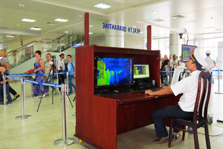 Kiểm dịch viên của Trung tâm Kiểm dịch Y tế quốc tế đang đo thân nhiệt của hành khách