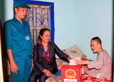 Tổ bầu cử mang thùng phiếu đến tận nhà để bà Đào Thị Này (ở đảo Trí Nguyên, phường Vĩnh Nguyên, TP. Nha Trang) bỏ phiếu bầu. Ảnh: M.H