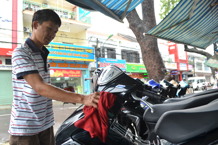 Nhân viên cửa hàng xe máy cũ Anh Tùng vệ sinh xe máy trong lúc vắng khách.