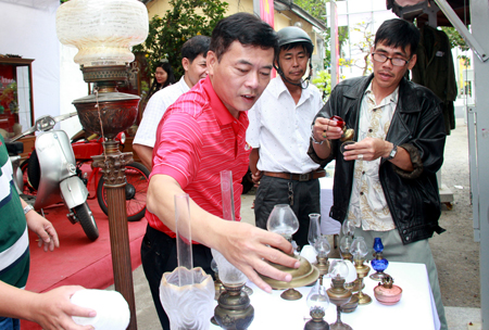 Ông Đào Hòa – Chủ nhiệm CLB cổ vật Nha Trang (áo đỏ) đang sắp xếp bộ sưu tập đèn xưa