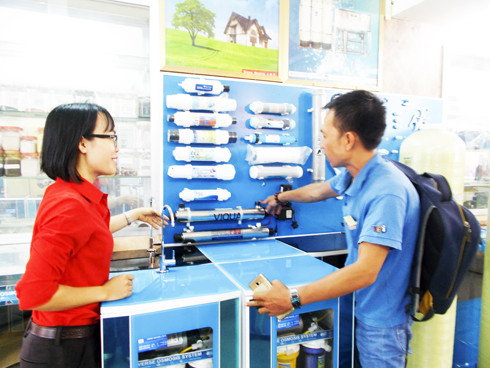 Một khách hàng (bên phải) đang được nhân viên Công ty Cổ phần  Thương mại và đầu tư Đăng Quang tư vấn về máy lọc nước