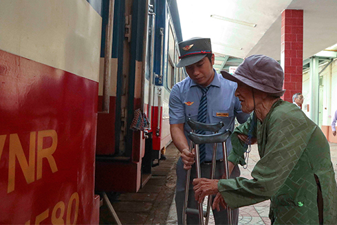 Nhân viên đường sắt giúp đỡ một cụ già lên tàu
