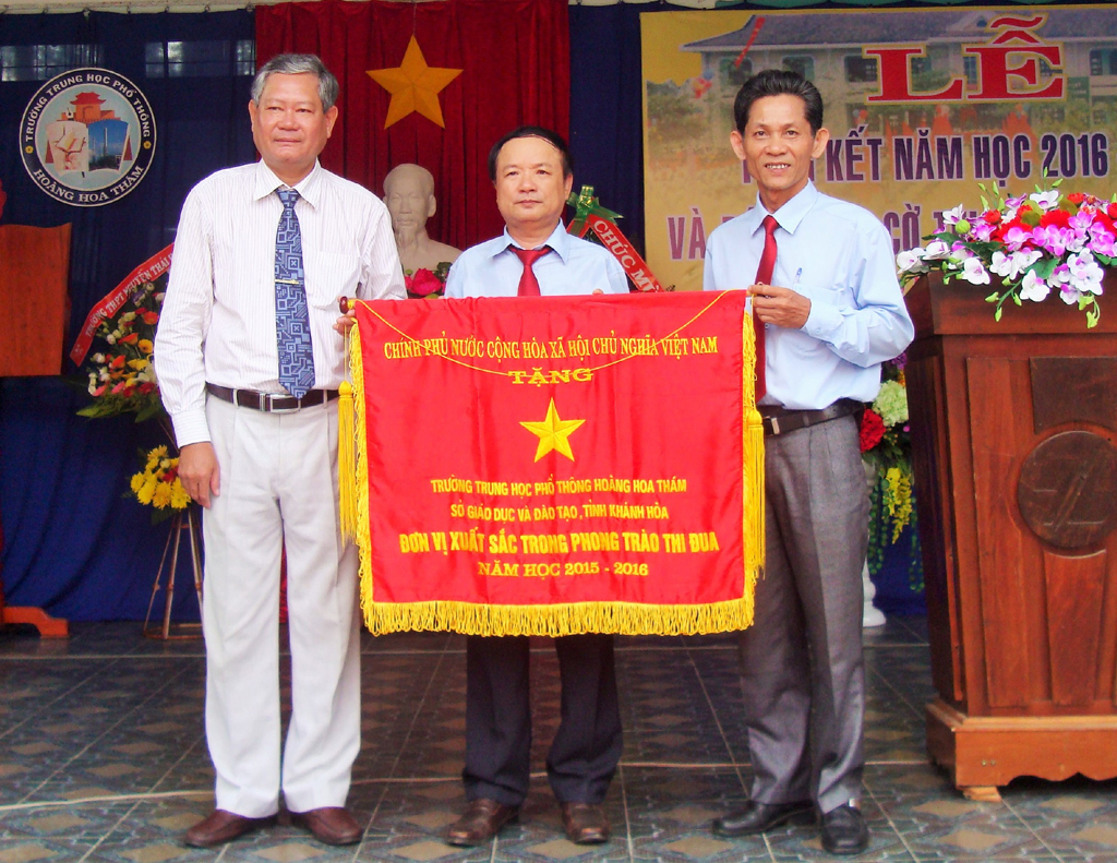 Trần Quang Mẫn – Phó Giám đốc Sở Giáo dục và Đào tạo Khánh Hòa (bìa trái) tặng cờ thi đua của Chính phủ cho nhà trường. 