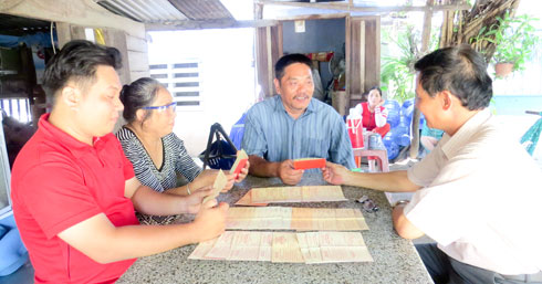 Ông Hồ Ngọc Tuấn (áo xanh, ngồi giữa) cùng vợ và con nhận thẻ hiến máu tình nguyện từ ông Hùng - Chủ tịch Hội Chữ thập đỏ phường Ba Ngòi.