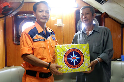 Lãnh đạo Trung tâm tìm kiếm, cứu nạn hàng hải khu vực 4 (bên trái) động viên, trao quà cho thuyền trưởng Cày.