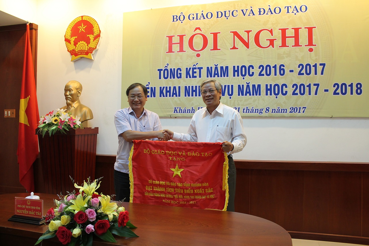 Đồng chí Nguyễn Đắc Tài (bên trái) trao cờ thi đua của Bộ GD-ĐT cho Sở GD-ĐT Khánh Hòa.