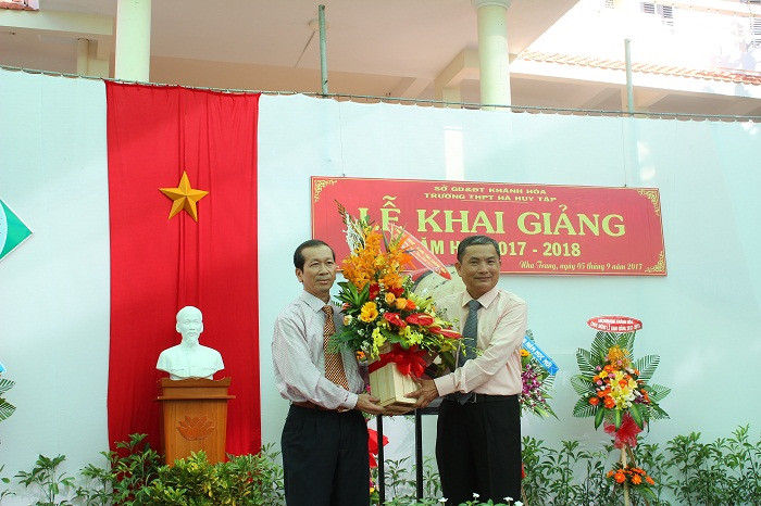 Ông Nguyễn Chuyện (bên trái) tặng hoa chúc mừng khai giảng cho lãnh đạo Trường THPT Hà Huy Tập