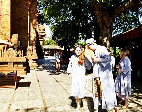 Du khách nước ngoài mặc áo tràng trước khi vào điện thờ ở di tích Tháp Bà Ponagar