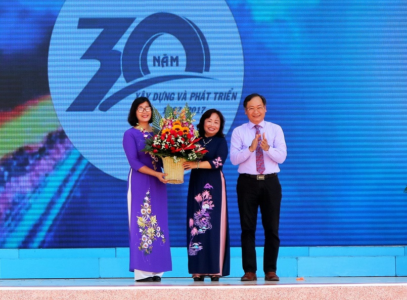 Ông Nguyễn Đắc Tài tặng hoa chúc mừng của UBND tỉnh cho nhà trường.