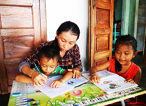 Cô Đinh Thị Xuân Duyên kèm cặp học sinh và con trai tập đọc, tập viết