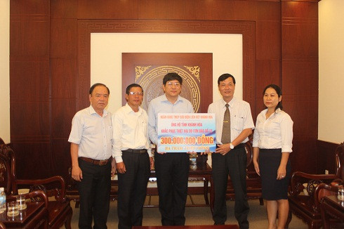 Lãnh đạo Ngân hàng Thương mại Cổ phần Bưu điện liên Việt Khánh Hòa (thứ 2 từ phải qua) trao hỗ trợ đồng bào bị thiệt hại do bão.