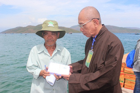 : Đại diện Ban trị sự Giáo hội Phật giáo Việt Nam huyện Vạn Ninh trao quà lại cho Phó thôn Ninh Đảo để phát cho người dân.