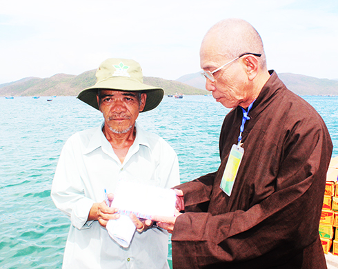 Đại diện Ban Trị sự Giáo hội Phật giáo Việt Nam  huyện Vạn Ninh trao quà cho Phó Trưởng thôn Ninh Đảo  để phát cho người dân