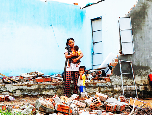 3 mẹ con chị H Nhiên ở Khánh Hiệp trước đống hoang tàn do bão gây ra