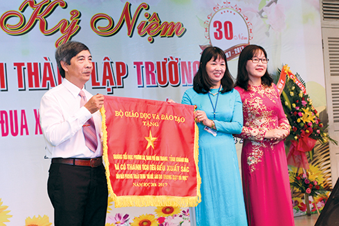 Bà Hoàng Thị Lý - Phó Giám đốc Sở GD-ĐT trao cờ thi đua xuất sắc của Bộ GD-ĐT cho lãnh đạo nhà trường