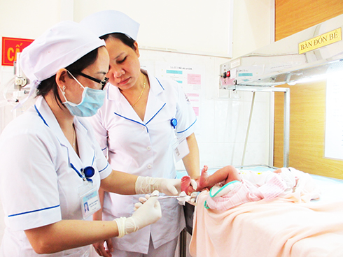 Cán bộ y tế lấy mẫu máu gót chân trẻ sơ sinh để sàng lọc sơ sinh