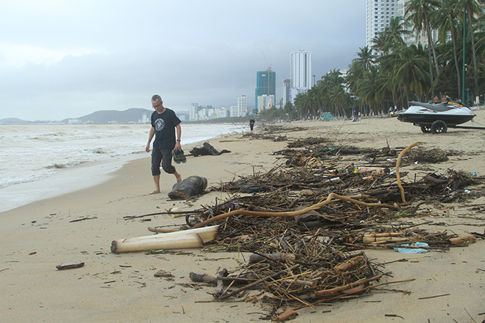 Một du khách nước ngoài đi dạo trên bãi biển đầy rác.