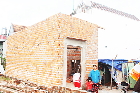 Gia đình bà Lê Thị Hồng Phượng bên căn nhà đang xây dựng dở dang.  