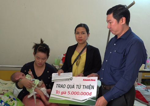 Đại diện Vietcombank Nha Trang và Báo Khánh Hòa trao tiền ủng hộ cho gia đình bé Lê Hồng Vũ. 