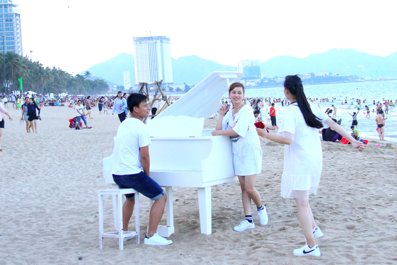 Khách du lịch thích thú tạo dáng với mô hình đàn dương cầm trên bãi biển