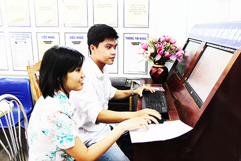 Công chức Sở Tư pháp (bìa trái) hỗ trợ người dân đăng ký nộp hồ sơ cấp phiếu lý lịch tư pháp trực tuyến.