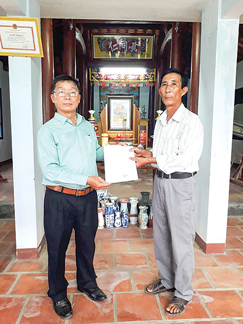 Lãnh đạo Chi cục Văn thư - Lưu trữ tỉnh (trái) trao quyết định công nhận tài liệu quý hiếm cho đại diện Ban quản lý đình Đồng Nhơn (xã Vĩnh Trung, TP. Nha Trang). 