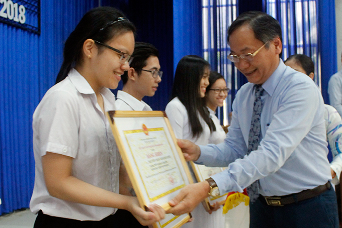 Ông Nguyễn Đắc Tài trao bằng khen cho học sinh đạt điểm cao.