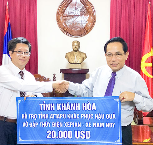 Ông Intha VôngPhaChanh (bìa phải) tiếp nhận tiền hỗ trợ của Khánh Hòa.
