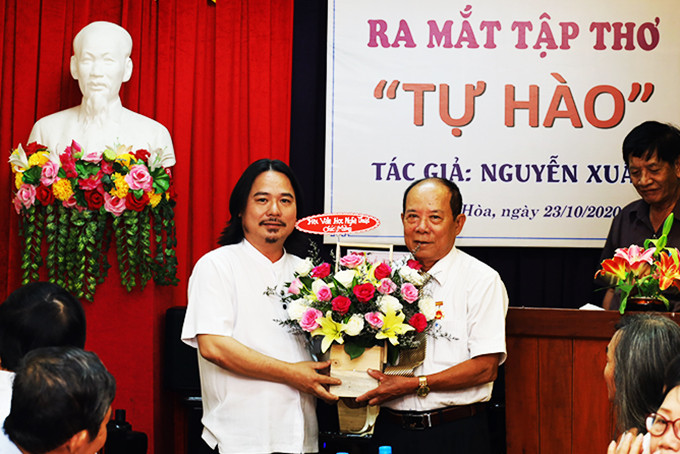 Lãnh đạo Hội Văn học Nghệ thuật tỉnh (bên trái) tặng hoa chúc mừng tác giả Nguyễn Xuân. 