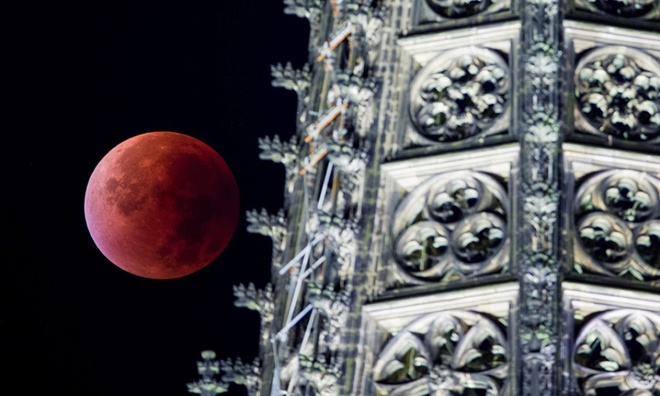 Trong thời gian diễn ra nguyệt thực toàn phần, ánh sáng Mặt trời bị khúc xạ và phân tán trên bề mặt Mặt trăng, khiến nó trông như có màu đỏ. Đây là hình ảnh siêu trăng đỏ bên cạnh một ngọn tháp của nhà thờ Cologne, Đức. Ảnh: Rolf Vennenbernd
