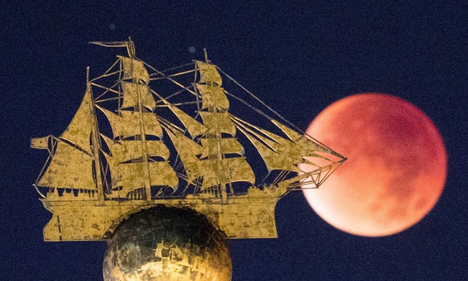 Siêu trăng đỏ xuất hiện sau bức tượng thuyền buồm ở Hamburg, Đức. Ảnh: Daniel Reinhardt