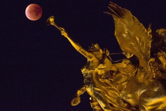Siêu trăng đỏ xuất hiện bên cạnh bức tượng trên cầu Alexander III tại Paris, Pháp. Ảnh: Reuters