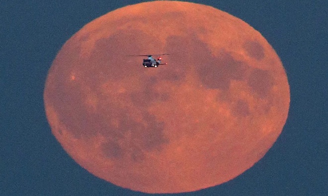 Một chiếc máy bay cứu hộ tình cờ bay ngang qua siêu trăng đỏ khi đang trên đường đến bờ biển Jurassic, Dorset, thuộc vùng tây nam nước Anh. Ảnh: Richard Austin.