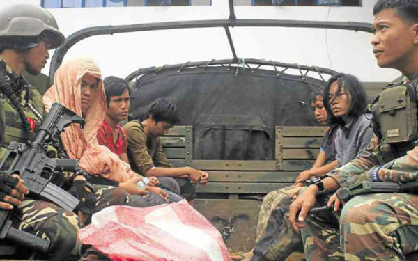 Quân đội Philippines (cầm súng) áp tải một số phần tử của nhóm Hồi giáo cực đoan Maute. Ảnh: Inquirer.net.