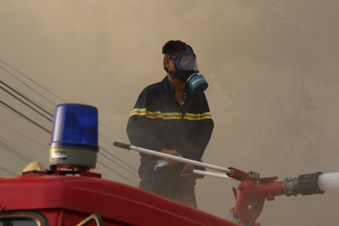 Lính cứu hỏa dùng mặt nạ phòng độc để dập lửa
