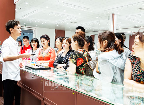 Khách du lịch Trung Quốc nghe hướng dẫn viên giới thiệu về sản phẩm đá quý.