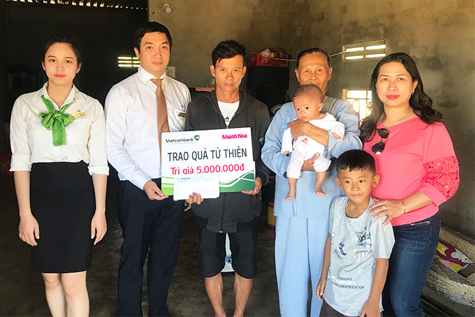 Đại diện Báo Khánh Hòa và Vietcombank Nha Trang trao tiền hỗ trợ cho gia đình 2 bé mồ côi mẹ.