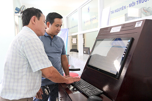 Công chức bộ phận một cửa UBND huyện hướng dẫn người dân đăng ký giải quyết hồ sơ trực tuyến.