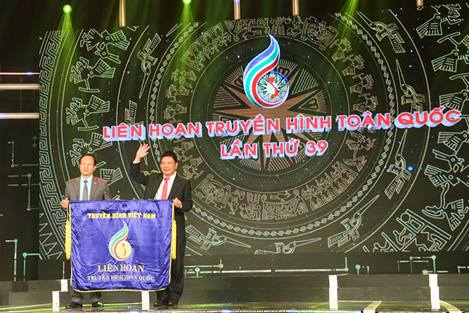 Lãnh đạo Đài Phát thanh và Truyền hình Khánh Hòa (phải) trao cờ đăng cai tổ chức Liên hoan cho đại diện Đài Phát thanh và Truyền hình Ninh Bình. 