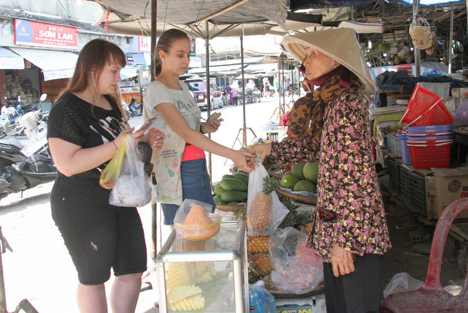 Hai nữ du khách Nga mua hoa quả ở bên ngoài Chợ Đầm, TP. Nha Trang