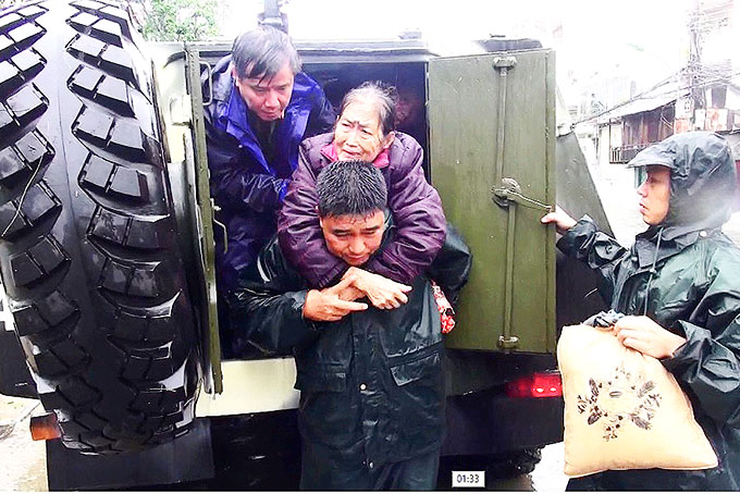 Cán bộ, chiến sĩ giúp sơ tán người dân đến nơi an toàn khi mưa bão (ảnh đơn vị cung cấp).