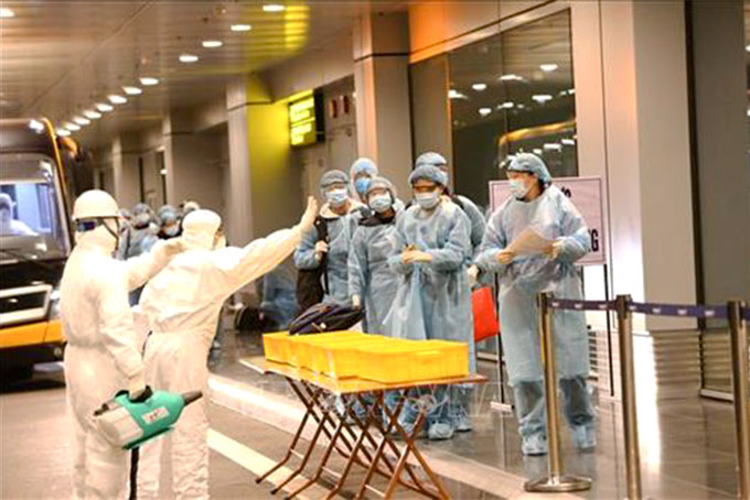 Công dân Việt Nam được khử trùng trước khi làm thủ tục nhập cảnh  tại sân bay Vân Đồn (tỉnh Quảng Ninh).