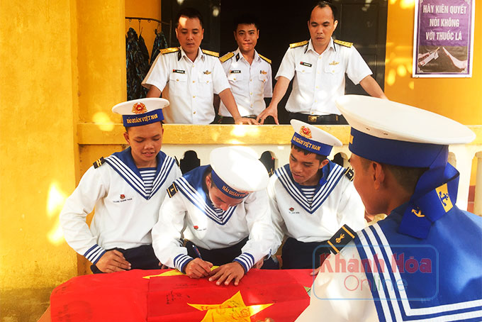  Các chiến sĩ đảo Sinh Tồn Đông ký tên vào cờ Tổ quốc tặng lại các đồng đội trở về đất liền.