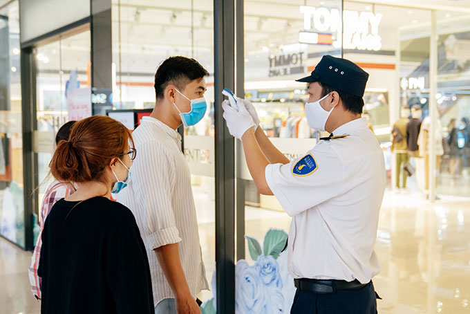 Nhân viên an ninh đo thân nhiệt toàn bộ khách ra/vào TTTM để giảm thiểu nguy cơ lây nhiễm chéo
