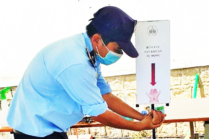 Nhân viên bảo vệ của nhà trường sử dụng máy rửa tay sát khuẩn tự động. 