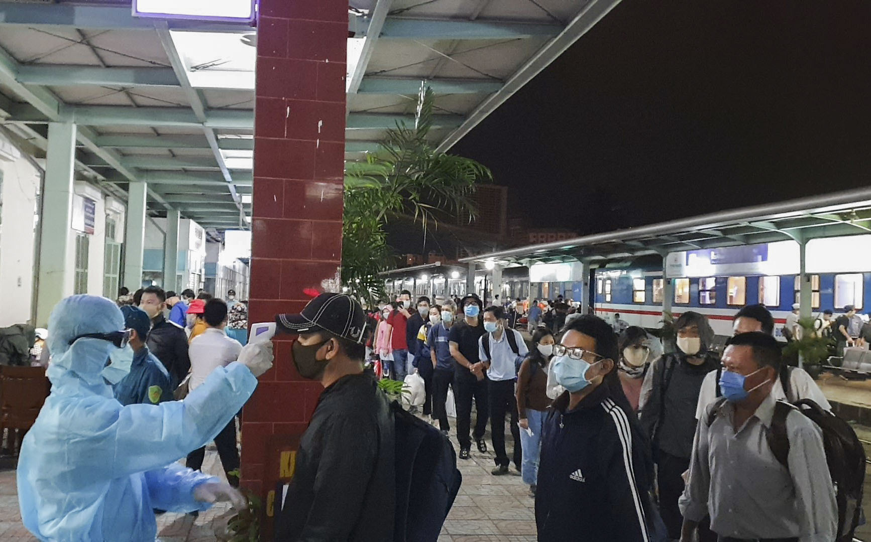 Tại ga Nha Trang, hành khách xếp hàng để đo thân nhiệt trước khi khai báo y tế.