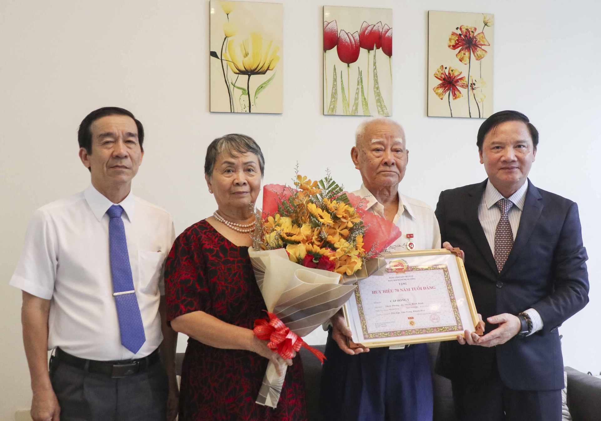 Ông Nguyễn Khắc Định (bìa phải) trao Huy hiệu 70 năm tuổi Đảng cho đảng viên lão thành Cáp Hồng Y.