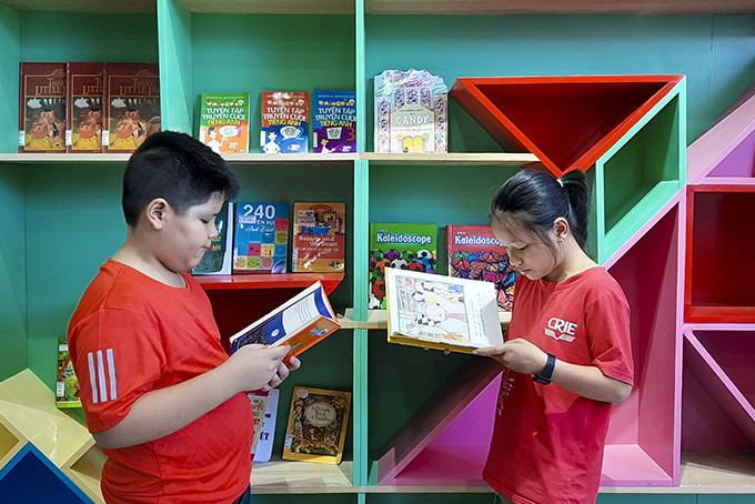 Độc giả thiếu nhi đọc sách tại trạm sách đặt ở Trung tâm ngoại ngữ quốc tế Tiên Phong.  